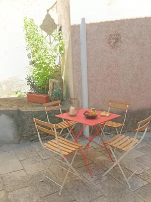a red table and chairs sitting on a patio at Entre mer et montagne in Valle-di-Campoloro