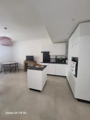 a kitchen with white cabinets and a table at T2 Ajaccio centre in Ajaccio