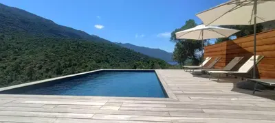 a swimming pool with two chairs and an umbrella at Casa Paula in Serriera