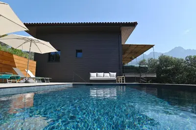 a swimming pool with an umbrella next to a house at Casa Paula in Serriera
