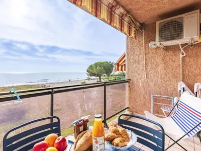 a table with food on a balcony with a view of the ocean at Studio Marines de Moriani by Interhome in Moriani Plage