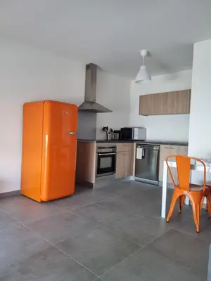 an orange refrigerator in a kitchen with a table and a chair at Napoland Appartement T2 recent in Ajaccio
