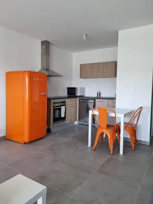a kitchen with an orange refrigerator and a table and chairs at Napoland Appartement T2 recent in Ajaccio