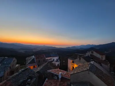 a sunset over a city with buildings and mountains at Appartement de charme - Nebbiu in Vallecalle