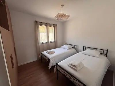 two twin beds in a room with a window at Appartements neuf, rio este in Viggianello