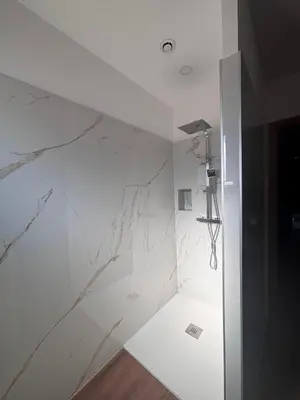 a bathroom with white marble walls and a shower at Appartements neuf, rio este in Viggianello