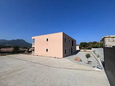 a large pink brick building on a road at Appartements neuf, rio este in Viggianello