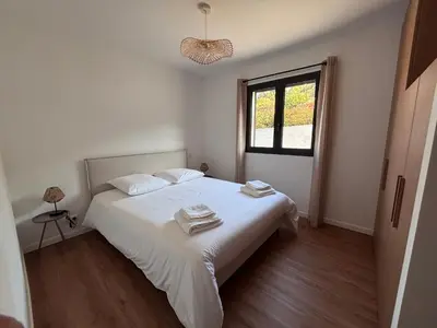 a bedroom with a bed with white sheets and a window at Appartements neuf, rio este in Viggianello