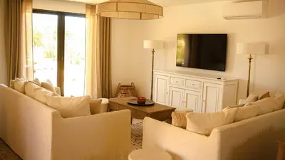 a living room with white furniture and a flat screen tv at Domaine de Gialla Bergerie Prugna, 6 pers, piscine chauffée, 10 mn plage in Arraggio