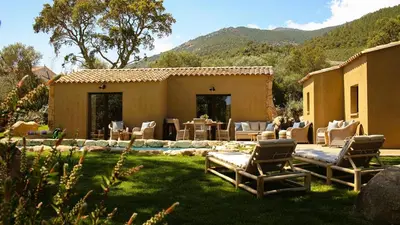a yard with chairs and a house with mountains in the background at Domaine de Gialla Bergerie Prugna, 2 pers, piscine chauffée, 10 mn plage in Arraggio