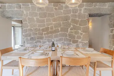 a dining room with a table with chairs and a stone wall at Torra di l alba in Viggianello