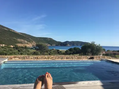 a person laying on the edge of a swimming pool at Les Bergeries d'Arone in Piana