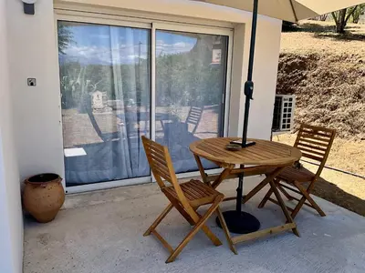 a table and two chairs with an umbrella on a porch at Chambre Studio chez l habitant in Alata
