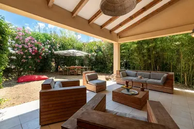 an outdoor patio with couches and chairs and an umbrella at Casa Bavitoli 1er étage - Avec jardin et terrasse in Cauro
