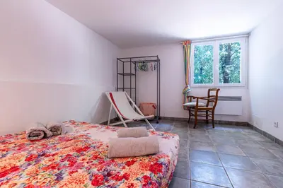 a bedroom with a bed and a chair and a window at Casa Bavitoli RDC - Avec jardin in Cauro