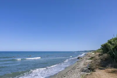 a beach with people swimming in the ocean at Casa Santa Lucia - Climatisé au bord de Mer in Santa-Lucia-di-Moriani