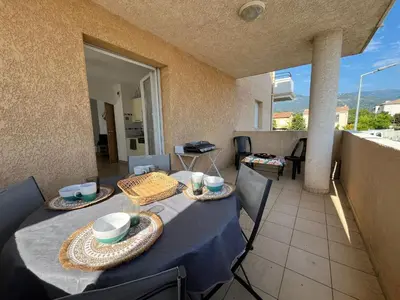 a table with a blue table cloth on a balcony at MORIANI Centre Lumineux T3 à deux pas de la mer et commerces in Moriani Plage