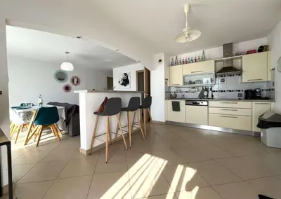 a kitchen with white cabinets and a table and chairs at MORIANI Centre Lumineux T3 à deux pas de la mer et commerces in Moriani Plage
