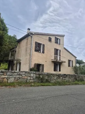 an old house on a stone wall next to a street at Maison de caractère in Pietrapola