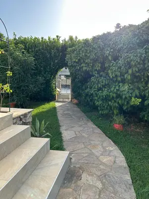 a garden with an archway and a stone path at Appartement A madonna in Santa-Lucia-di-Moriani