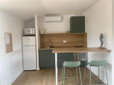 a kitchen with a table and two chairs and a refrigerator at Appartement A madonna in Santa-Lucia-di-Moriani
