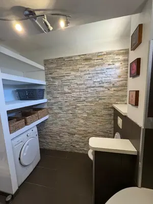 a bathroom with a washer and a brick wall at F3 parking gratuit Clim port 5min aéroport 10min in Ajaccio