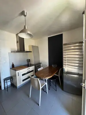 a kitchen with a table and chairs and a refrigerator at F3 parking gratuit Clim port 5min aéroport 10min in Ajaccio