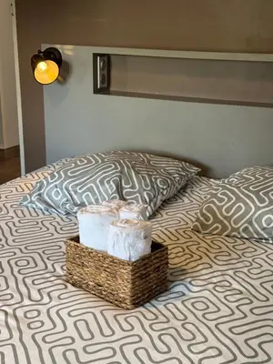a bed with a basket of towels and a pillow at F3 parking gratuit Clim port 5min aéroport 10min in Ajaccio