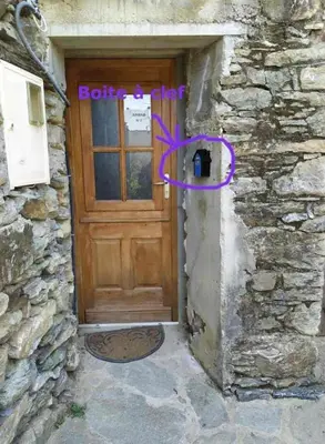 a wooden door in a stone building with a sign on it at Vue sur les montagnes Corses in Castellare-di-Mercurio