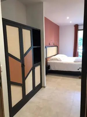 a bedroom with a bed and a sliding door at Hôtel du Golfe Pinarello in Pinarellu