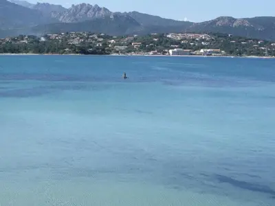 a large body of water with a city in the background at Hôtel du Golfe Pinarello in Pinarellu