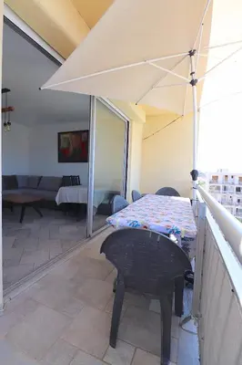 a balcony with a table and an umbrella at Spacieux Appartement Vue Mer et Montagne en dernier étage avec Terrasse - Parking et Wifi in Ajaccio