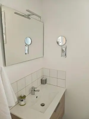 a white bathroom with a sink and a mirror at Maison Bois in Grosseto-Prugna