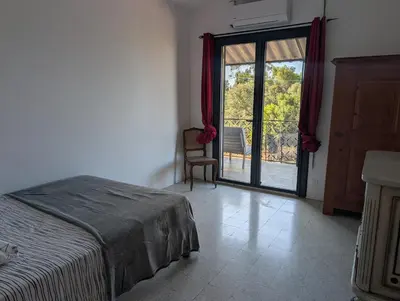 a bedroom with a bed and a sliding glass door at Andemu Pianottoli Caldarello in Pianottoli-Caldarello