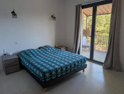 a bedroom with a bed and a door to a patio at Andemu Pianottoli Caldarello in Pianottoli-Caldarello