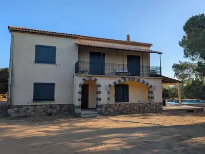 an old white house with a balcony on top at Andemu Pianottoli Caldarello in Pianottoli-Caldarello