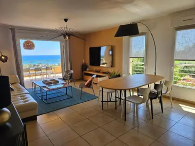 a living room with a table and chairs and the ocean at Appartement Paolina Vue Mer Sari-Solenzara Corse in Sari Solenzara
