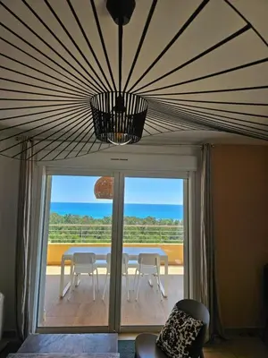 a room with a table and chairs and a large window at Appartement Paolina Vue Mer Sari-Solenzara Corse in Sari Solenzara