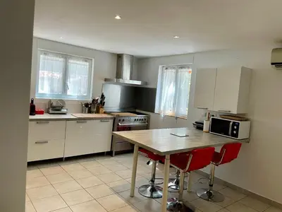 a kitchen with a wooden table and red chairs at La Milange de Porto vecchio in Porto-Vecchio