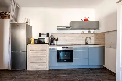 a kitchen with blue cabinets and a stainless steel refrigerator at Azur Ajaccien - Proche du port avec parking in Ajaccio