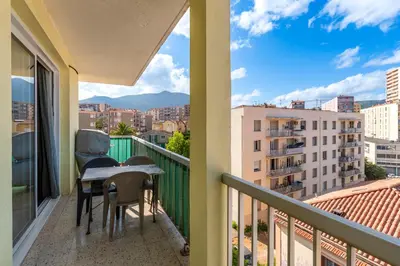 a balcony with a table and chairs and a view of a city at Azur Ajaccien - Proche du port avec parking in Ajaccio