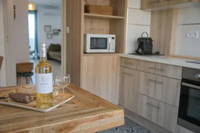 a bottle of wine and a glass on a table in a kitchen at Helena - Bright 2Br Trottel Beach by foot - by TGB in Ajaccio