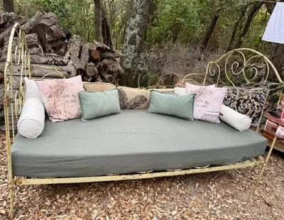 a bed with pillows on it in a garden at Appartement Porto-Vecchio in Porto-Vecchio
