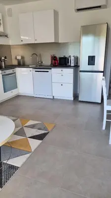 a kitchen with white cabinets and a refrigerator at BELLE Demeure in Pietrosella