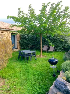 a grill in a yard with a table and a tree at Clos Simoni in Figari