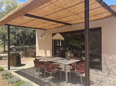 an outdoor dining area with a wooden table and chairs at Villa neuve pinarello avec piscine privée, plage à 450m in Zonza