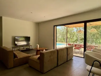 a living room with couches and a television and a patio at Villa neuve pinarello avec piscine privée, plage à 450m in Zonza