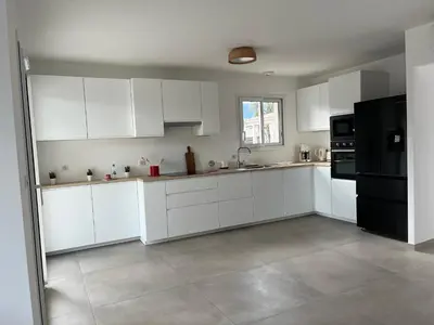 a kitchen with white cabinets and a black refrigerator at Villa L et Villa J in Prunelli-di-Fiumorbo