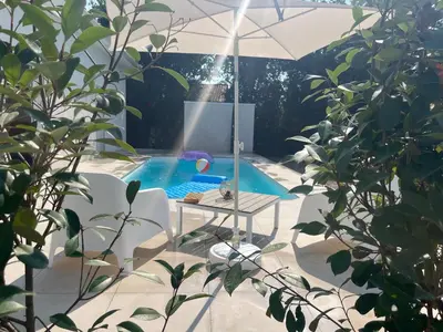 a swimming pool with a table and an umbrella at Villa L et Villa J in Prunelli-di-Fiumorbo