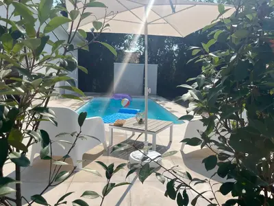 a swimming pool with a table and an umbrella at Villa L et Villa J in Prunelli-di-Fiumorbo